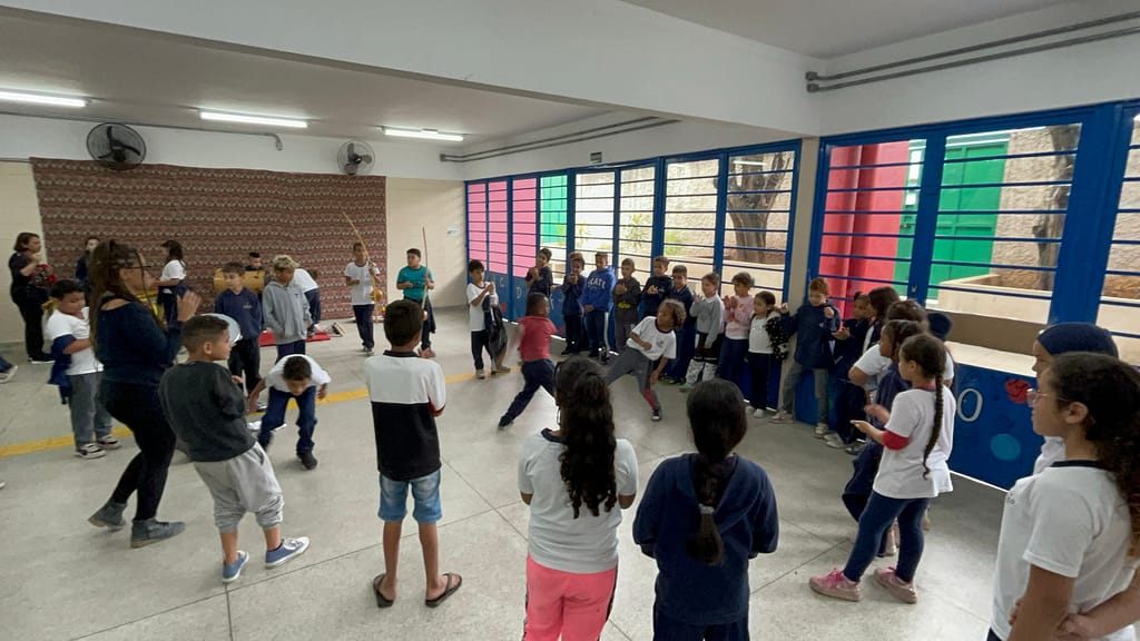 Crianças do Ciclo Interdisciplinar brincando de capoeira durante o intervalo, sob incentivo das professoras Ruth e Barbara.